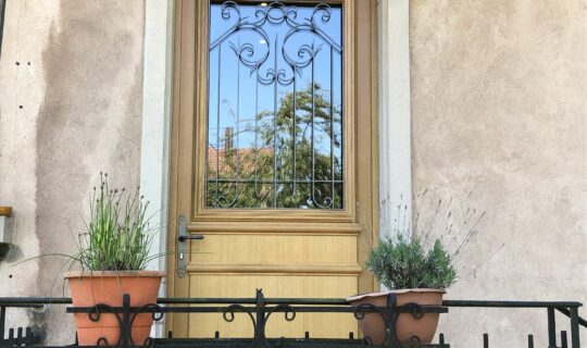 Une porte d'entrée sur mesure en bois avec un vitrail et une poignée en laiton.
